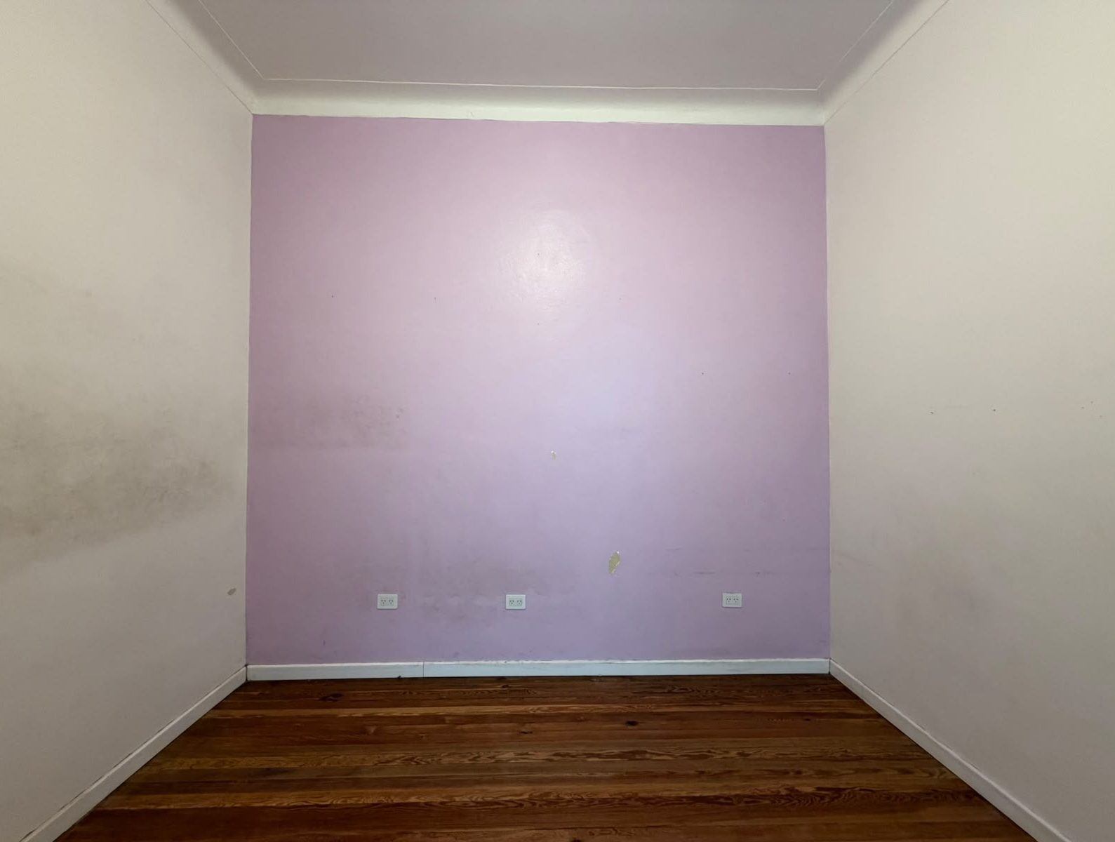 Antes: pared lila con tres enchufes y paredes blancas