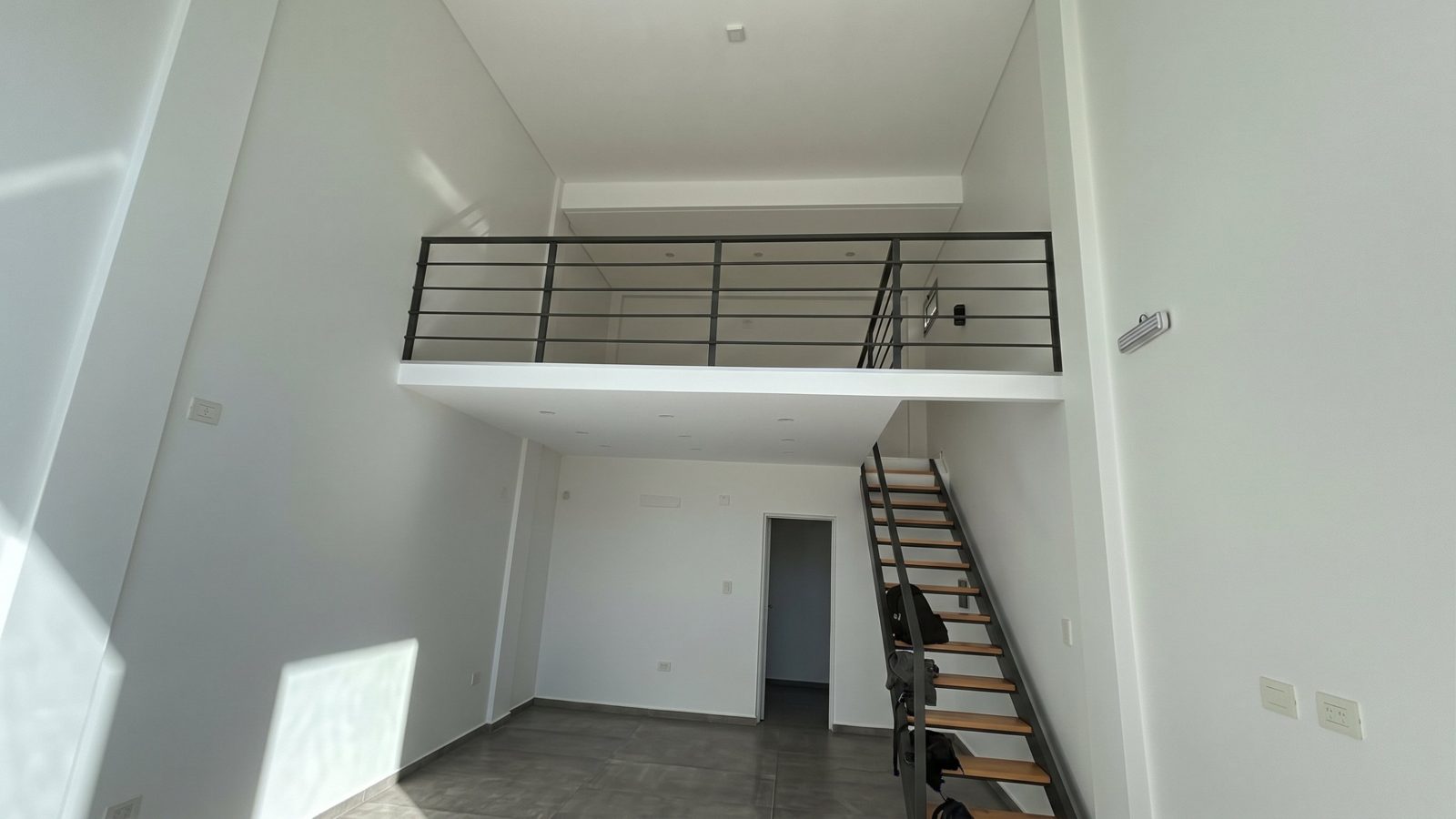 Antes: local blanco de doble altura con entrepiso y escalera de chapa y madera